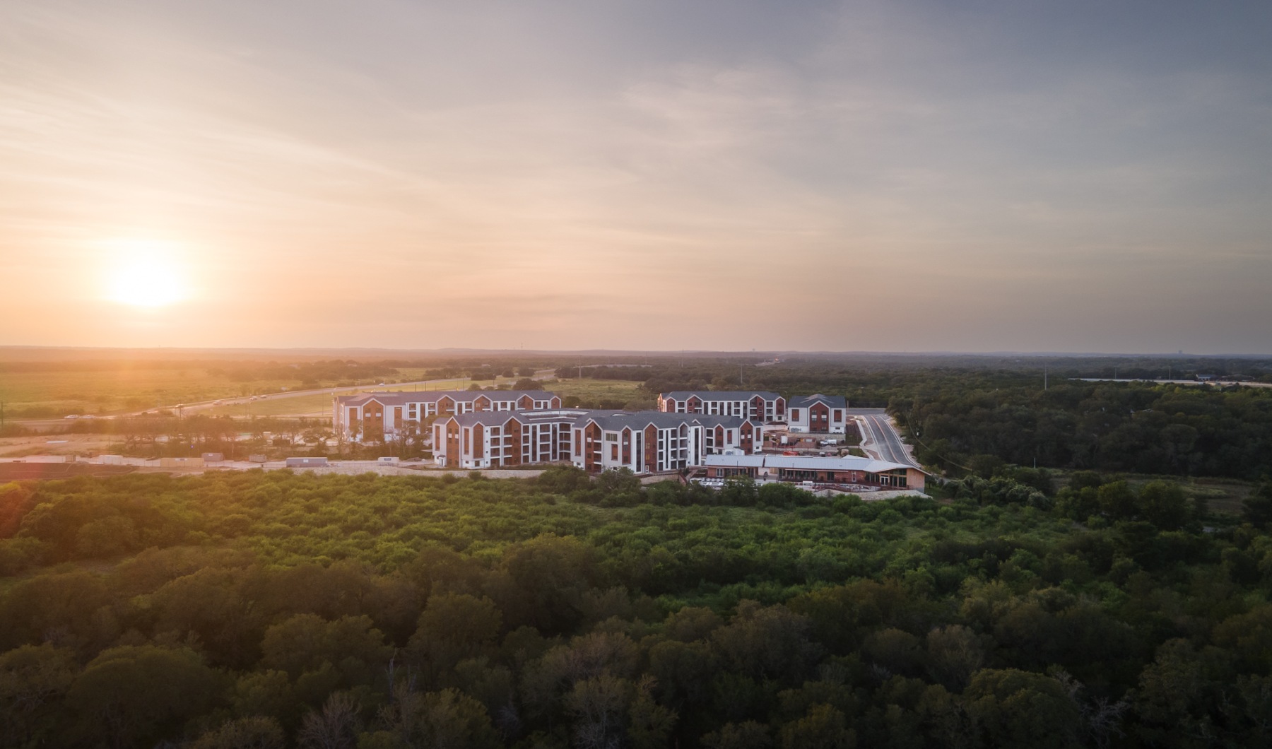 Drone photo of apartment complex with lush trees surrounding the area
